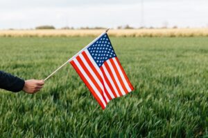 Photo by Karolina Grabowska of person holding an American Flag on the field.
